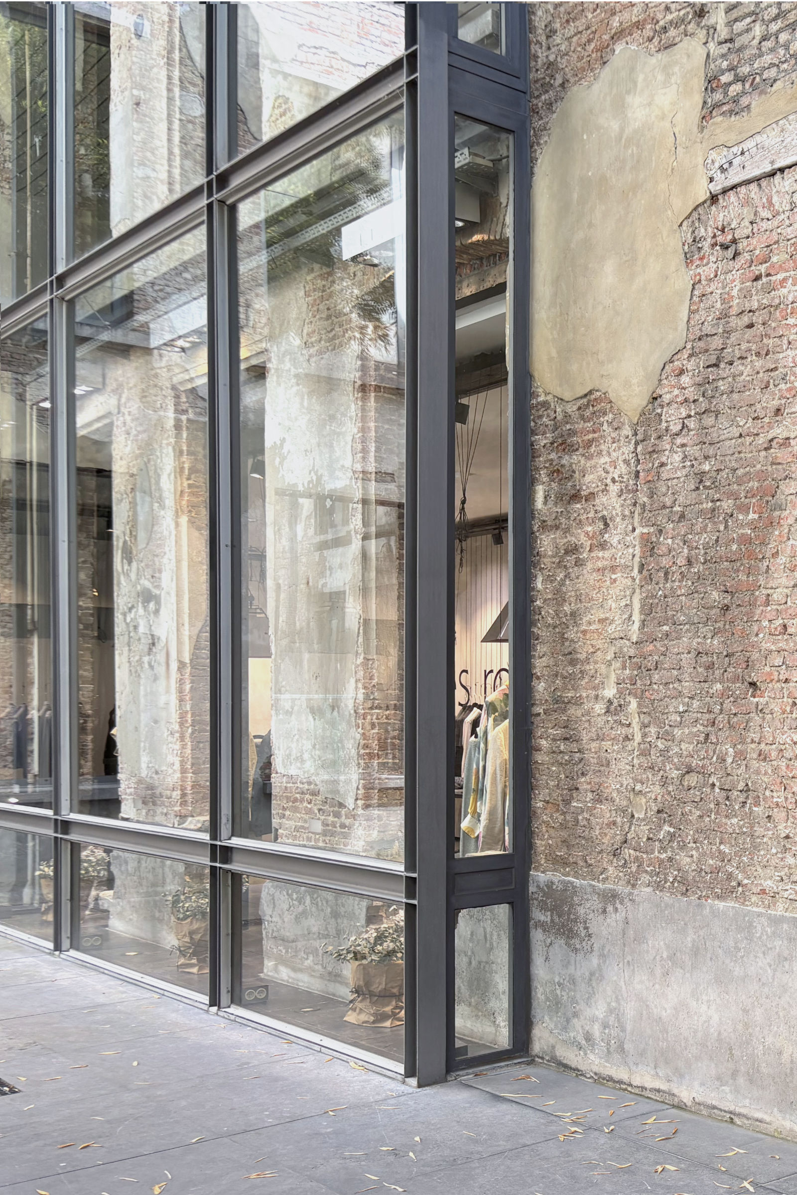 Detail einer modernen Stahl-Glas-Fassade vor einer historischen Backsteinfassade in einem Innenhof in Antwerpen