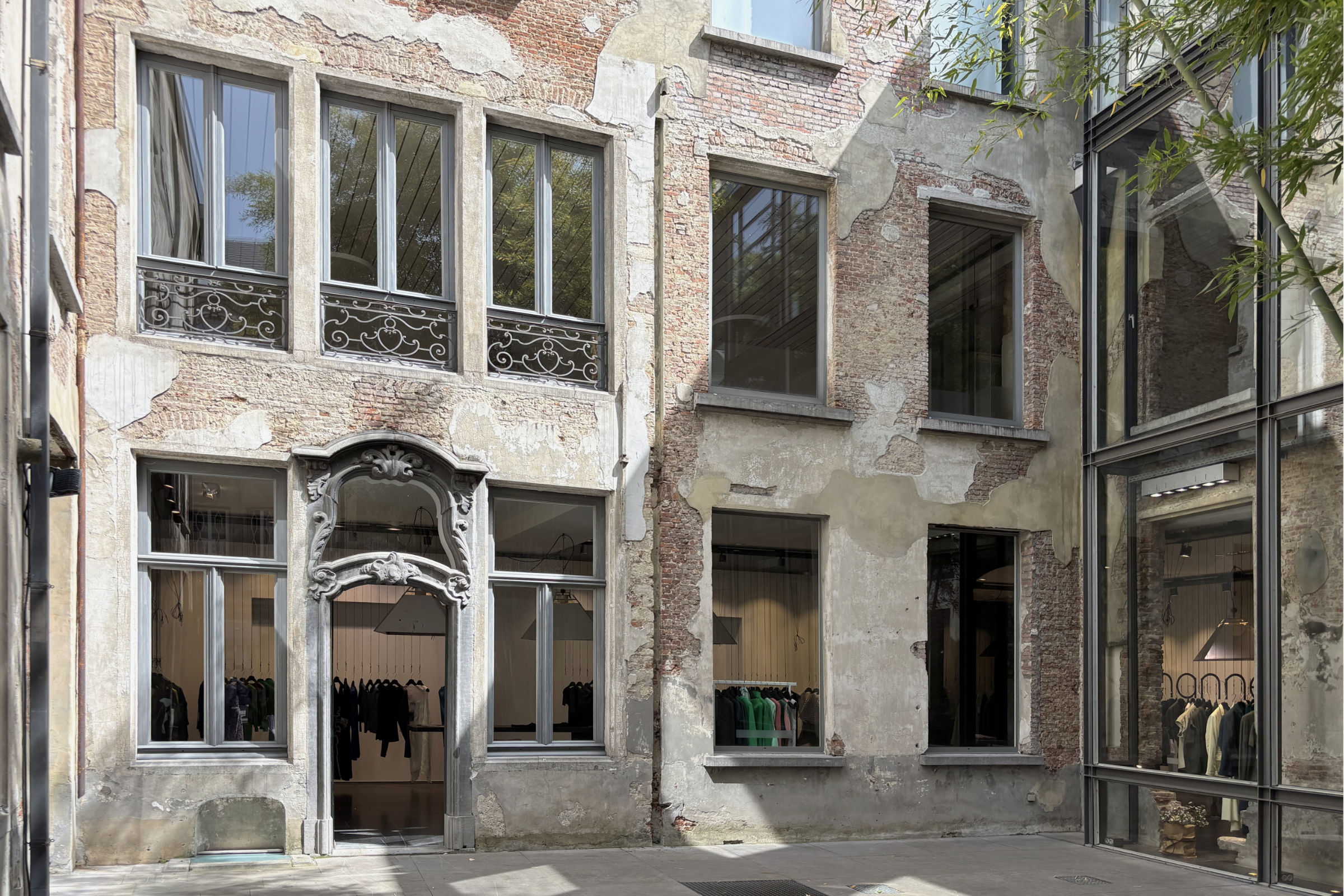 Historische Bestandsfassade mit freigelegtem Mauerwerk und barockem Portal in einem Innenhof in Antwerpen