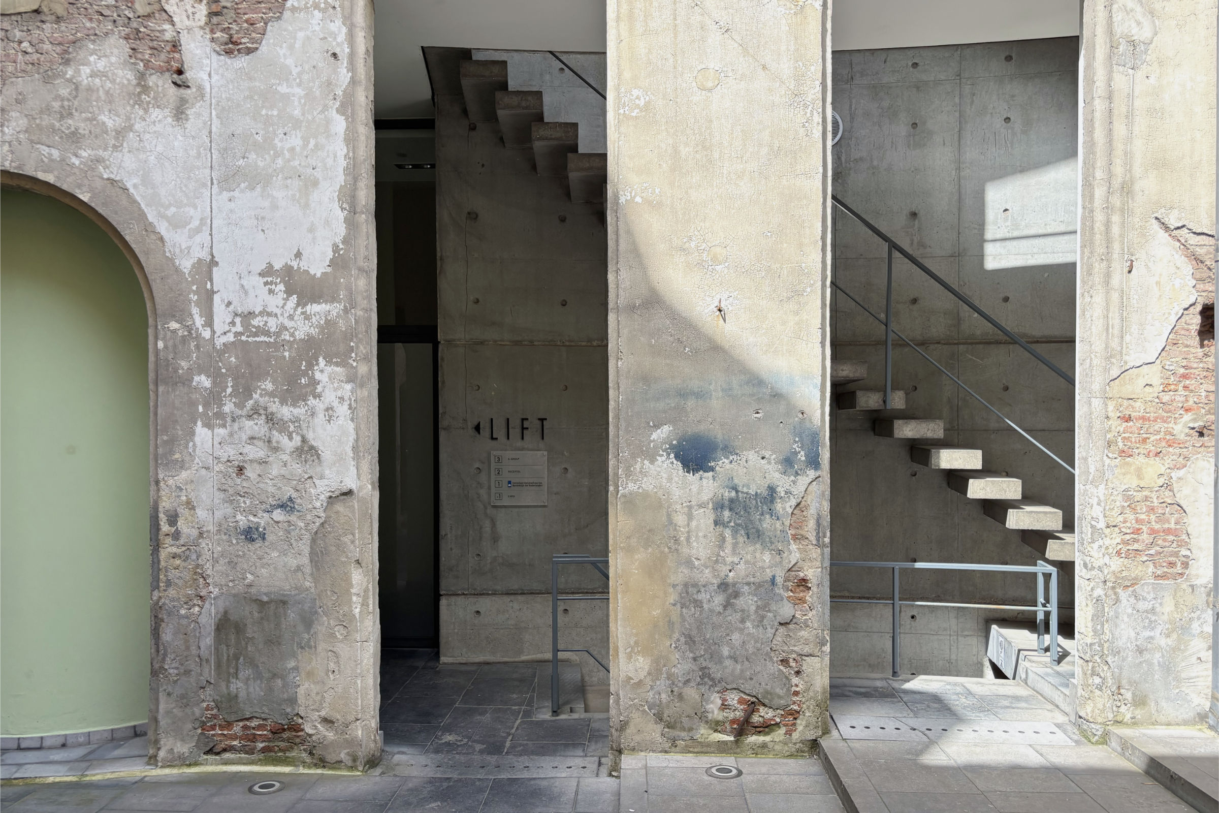 Betontreppe und Aufzug als moderner Einbau innerhalb einer historischen Bestandsfassade in einem Innenhof in Antwerpen