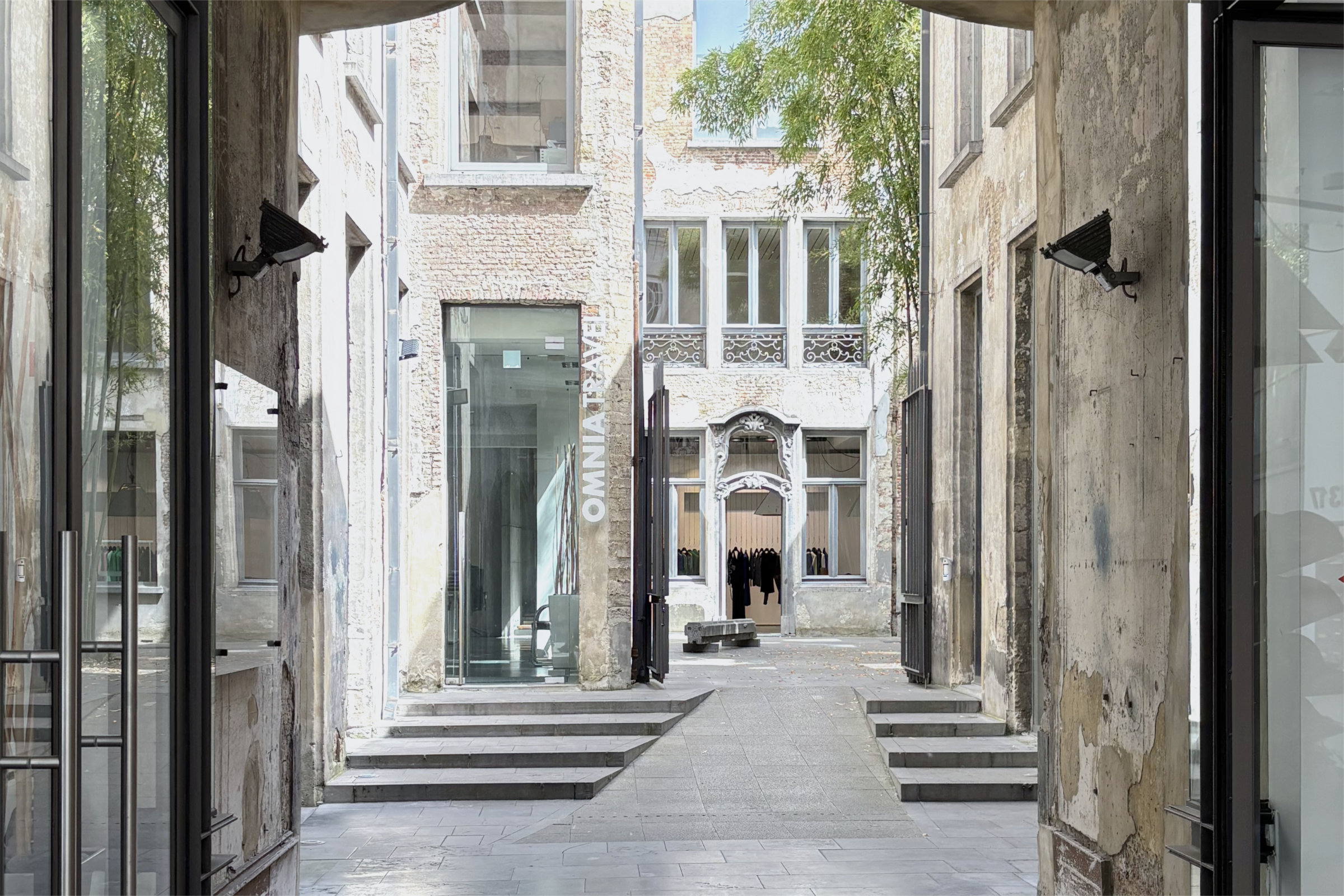 Blick durch einen Tordurchgang mit historischen Fassaden und modernen Glaseinbauten in einen Innenhof in Antwerpen