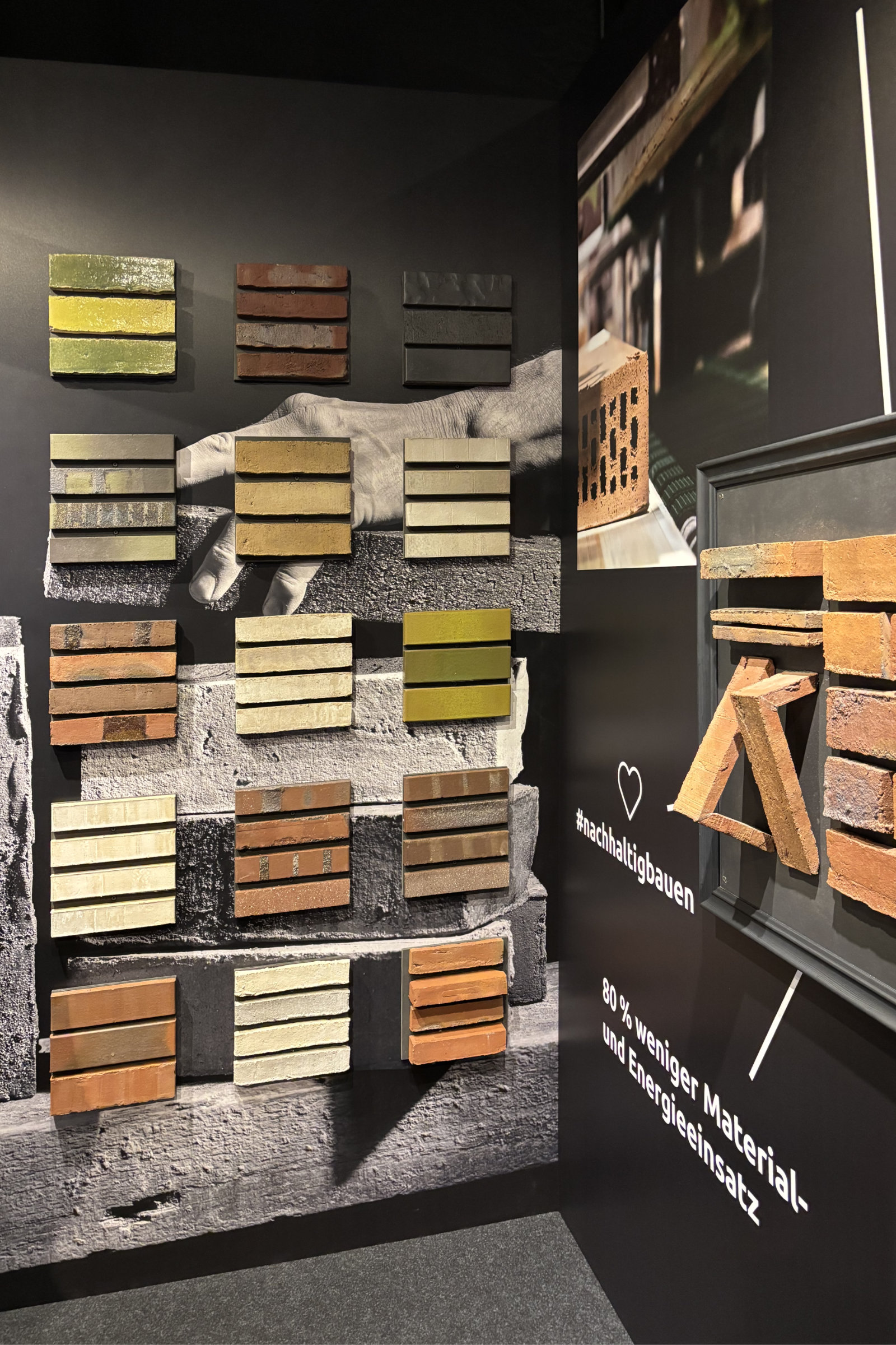 JPA_Aktuelles_architectatwork_1 Messestand auf der architect@work mit farblich sortierten Klinkersteinen und dem Hinweis auf 80 % weniger Material- und Energieeinsatz