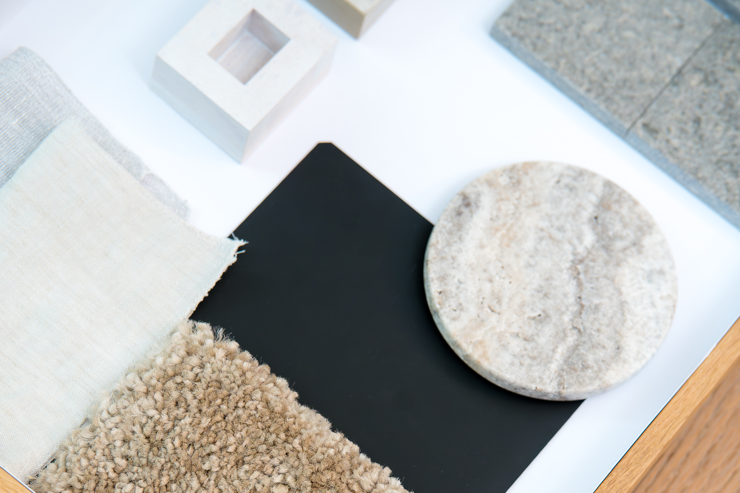 Materialauswahl aus Naturstein, Textilien und dunklen Oberflächen für ein Architektur- und Innenraumkonzept