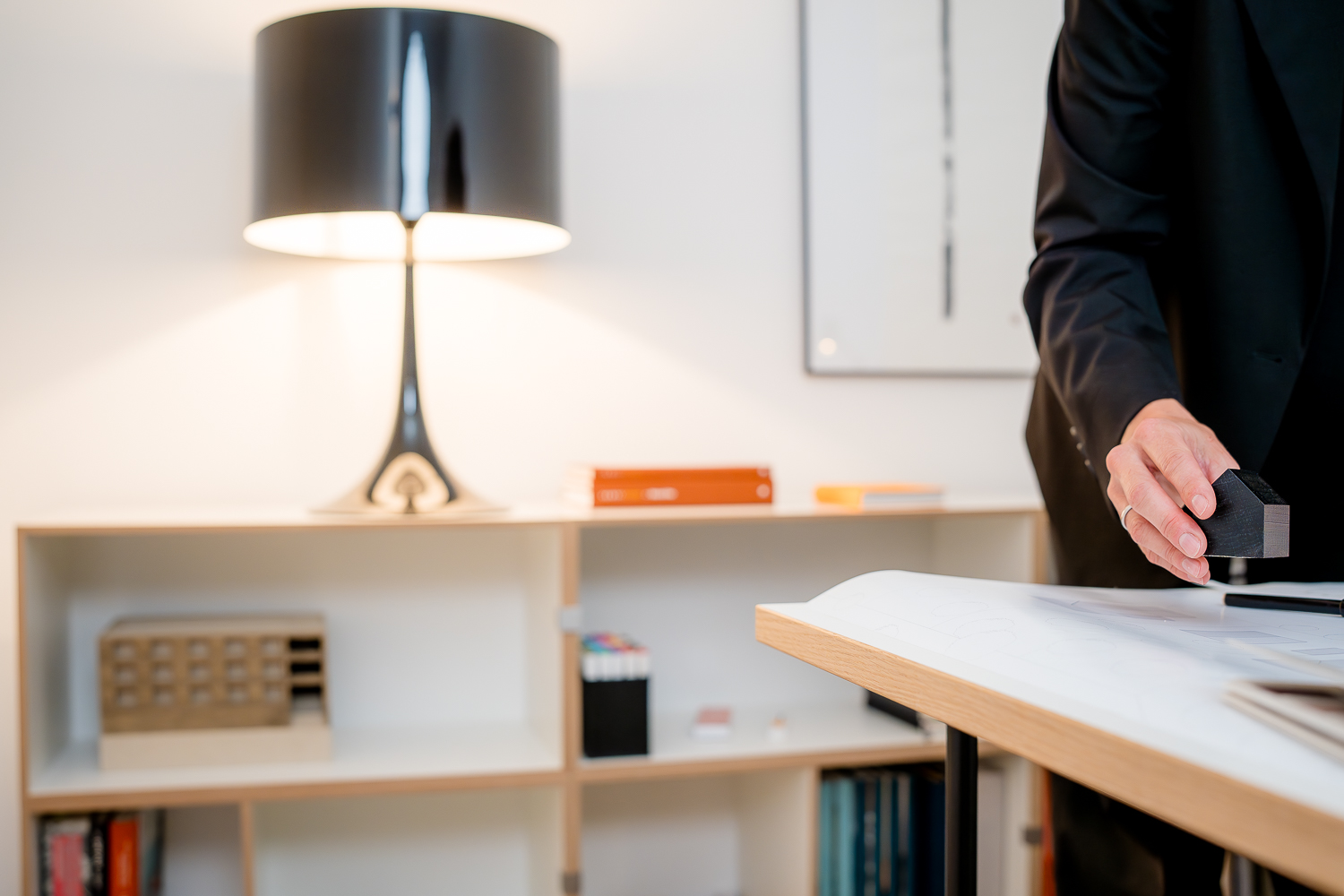 Detailaufnahme Hand von Architektin Jacqueline Preßmann mit einem Architekturmodell während der Entwicklung eines individuellen Entwurfskonzepts, im Hintergrund unscharf das Büro