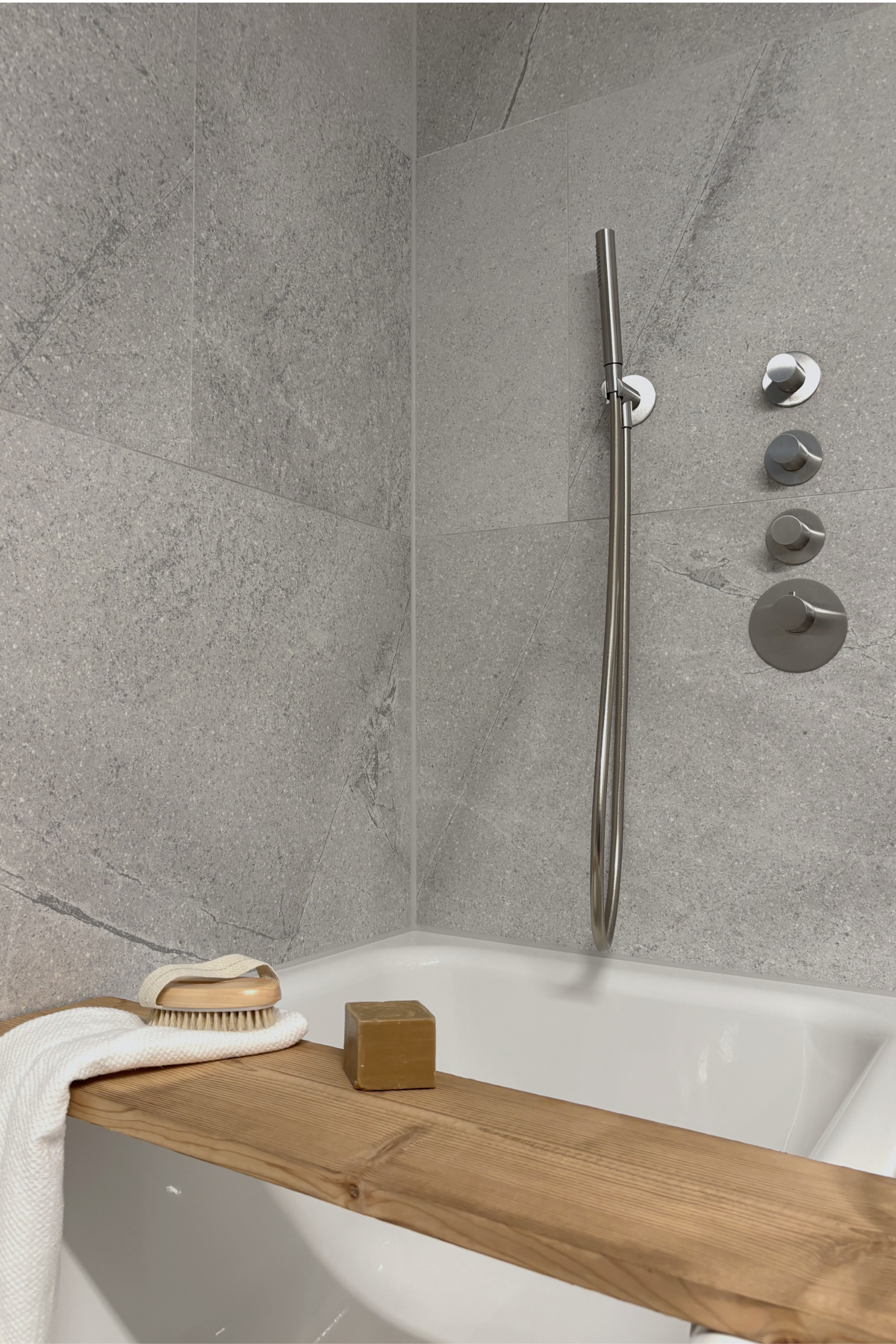 Bad 2: Detail der Badewanne aus Emaille mit Holzablage aus Tiroler Altholz, großformatigem grauem Feinsteinzeug und Edelstahlarmaturen