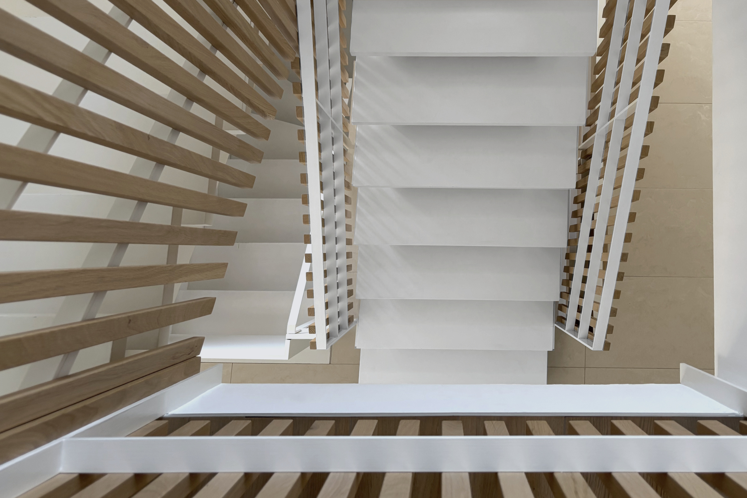 Treppe: Blick von oben durch das Treppenauge, weiß lackierte Treppe mit filigranem Stahlgeländer und vertikalen Lamellen aus Eichenholz